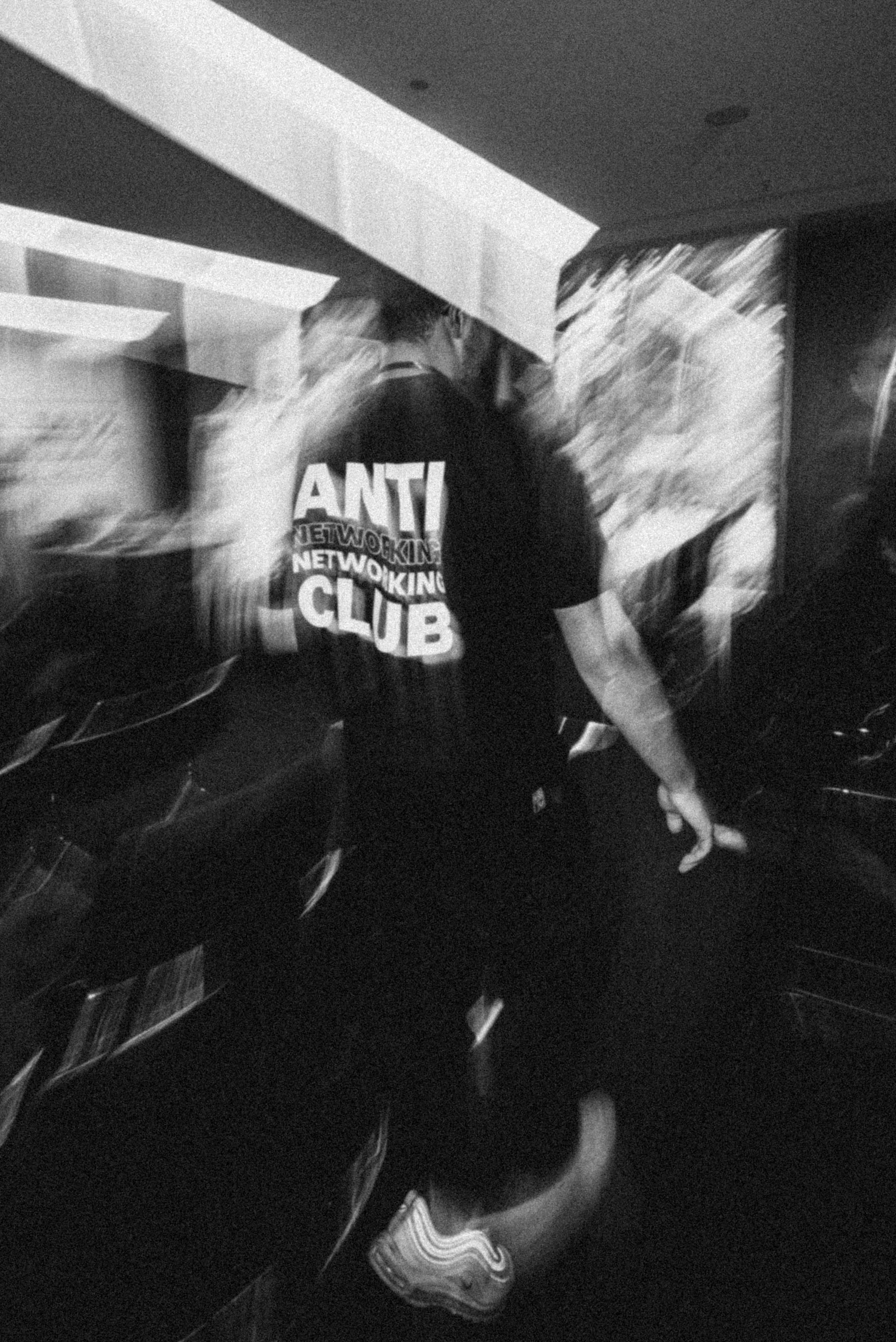 Motion-blurred figure in an ANTI NETWORKING NETWORKING CLUB shirt